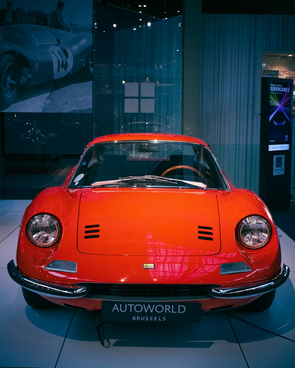 an orange sports car on display in a museum