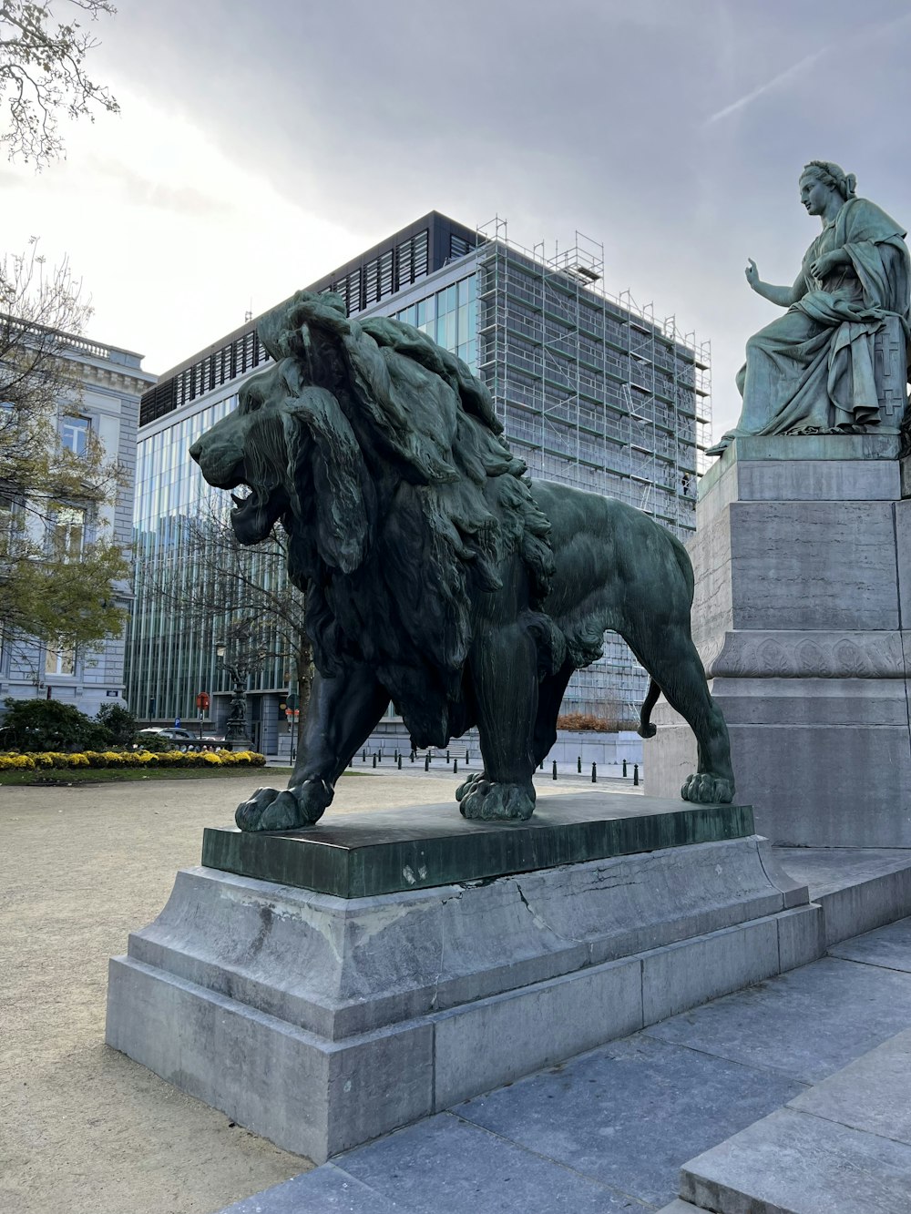 a statue of a lion and a woman in a city square