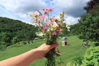 A joyful traveler holding a bouquet of wildflowers, smiling against a backdrop of rolling hills.