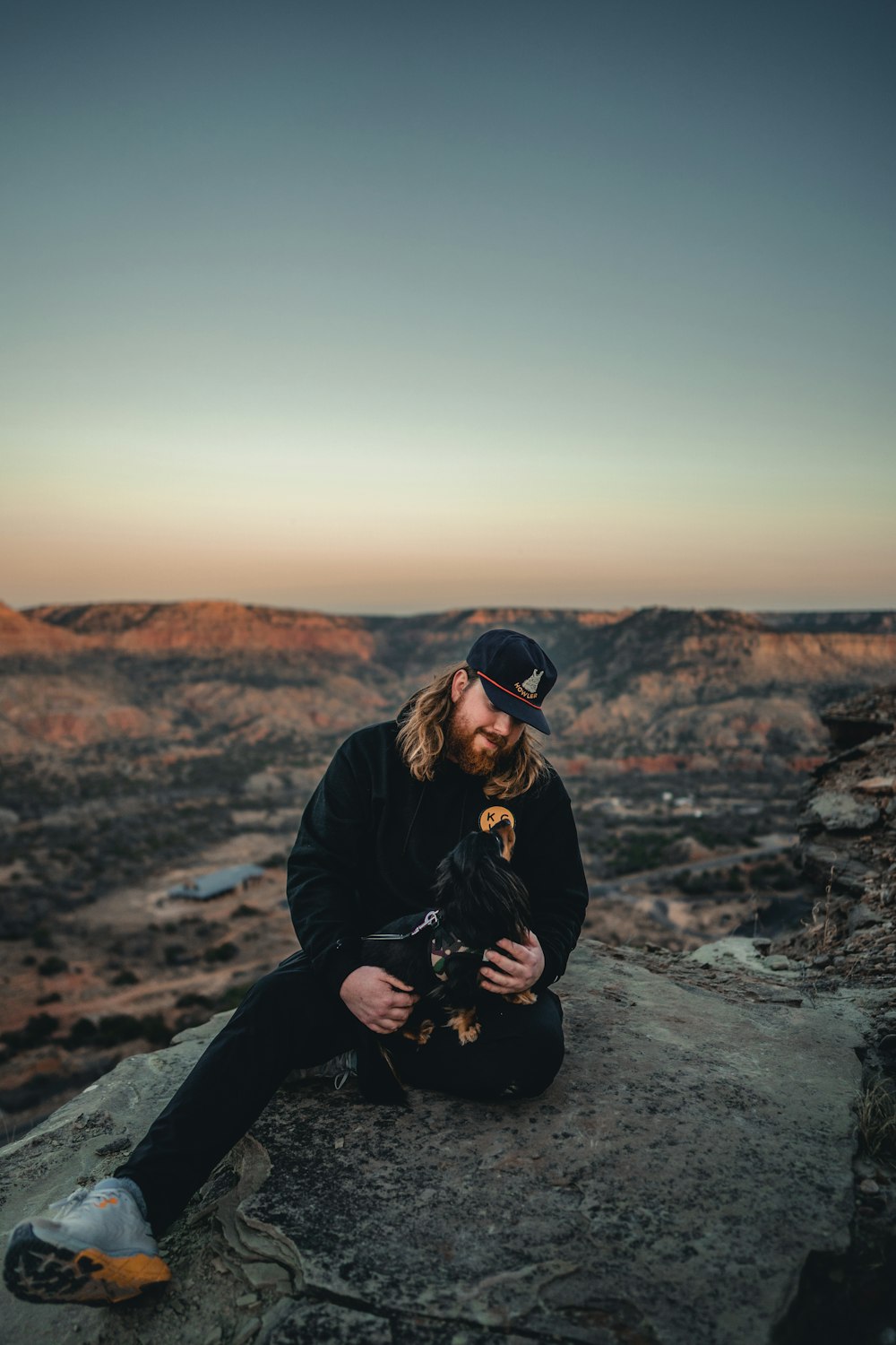 a man sitting on a rock with a dog