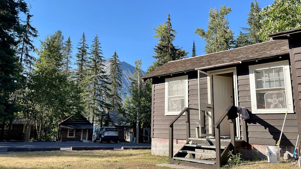 a small cabin in the woods with a car parked in front of it