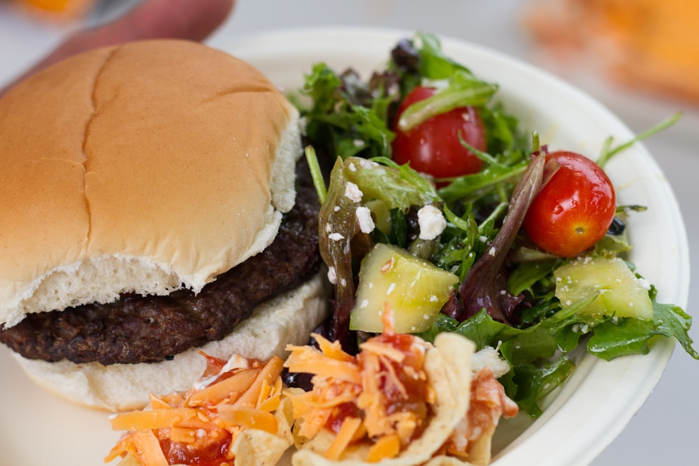 a hamburger and salad on a paper plate