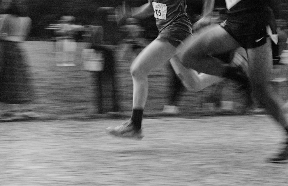 a black and white photo of two people running
