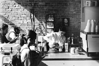 Barista preparing coffee behind a rustic counter with cups and coffee equipment.