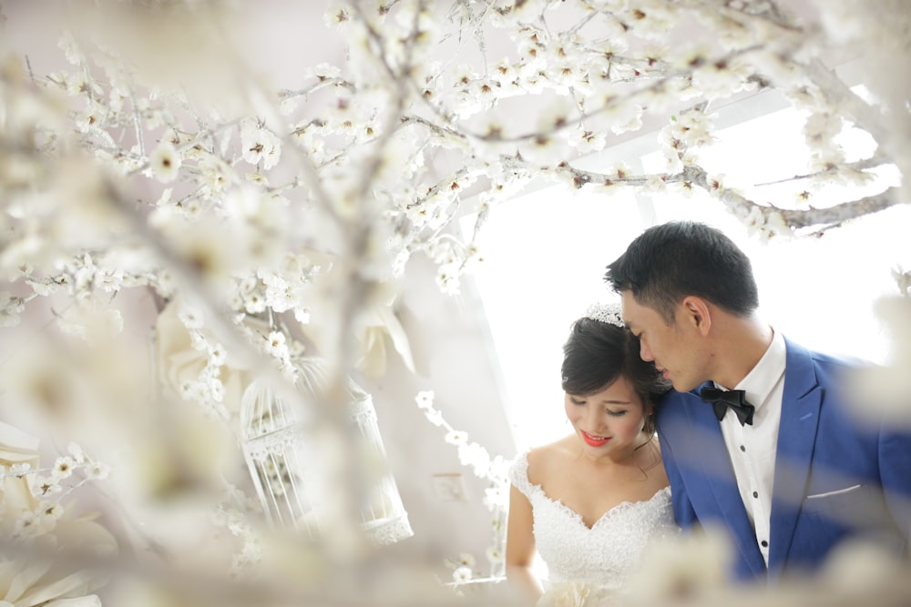 a man and a woman standing next to each other in front of a tree