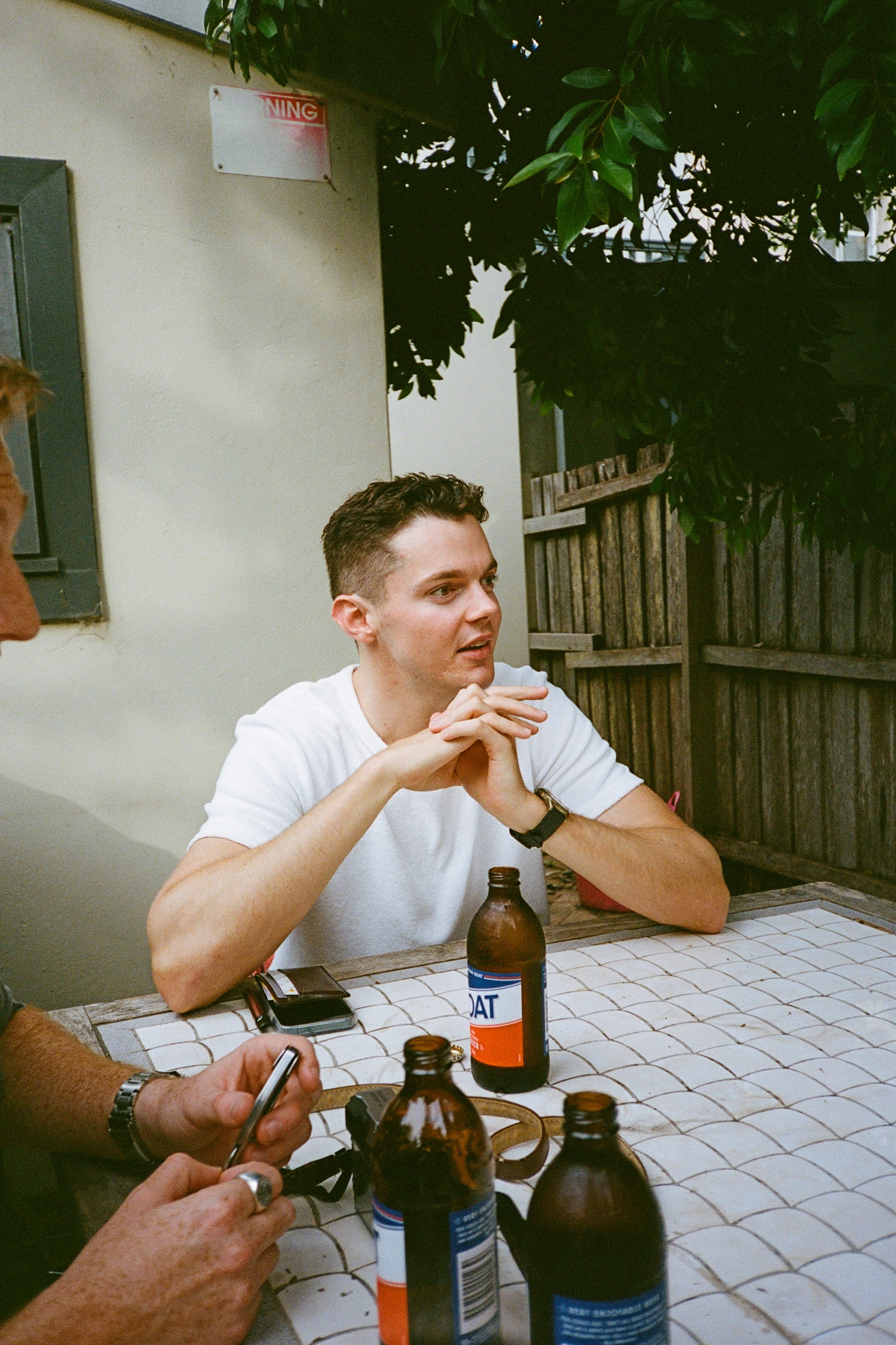 two men sitting at a table with bottles of beer