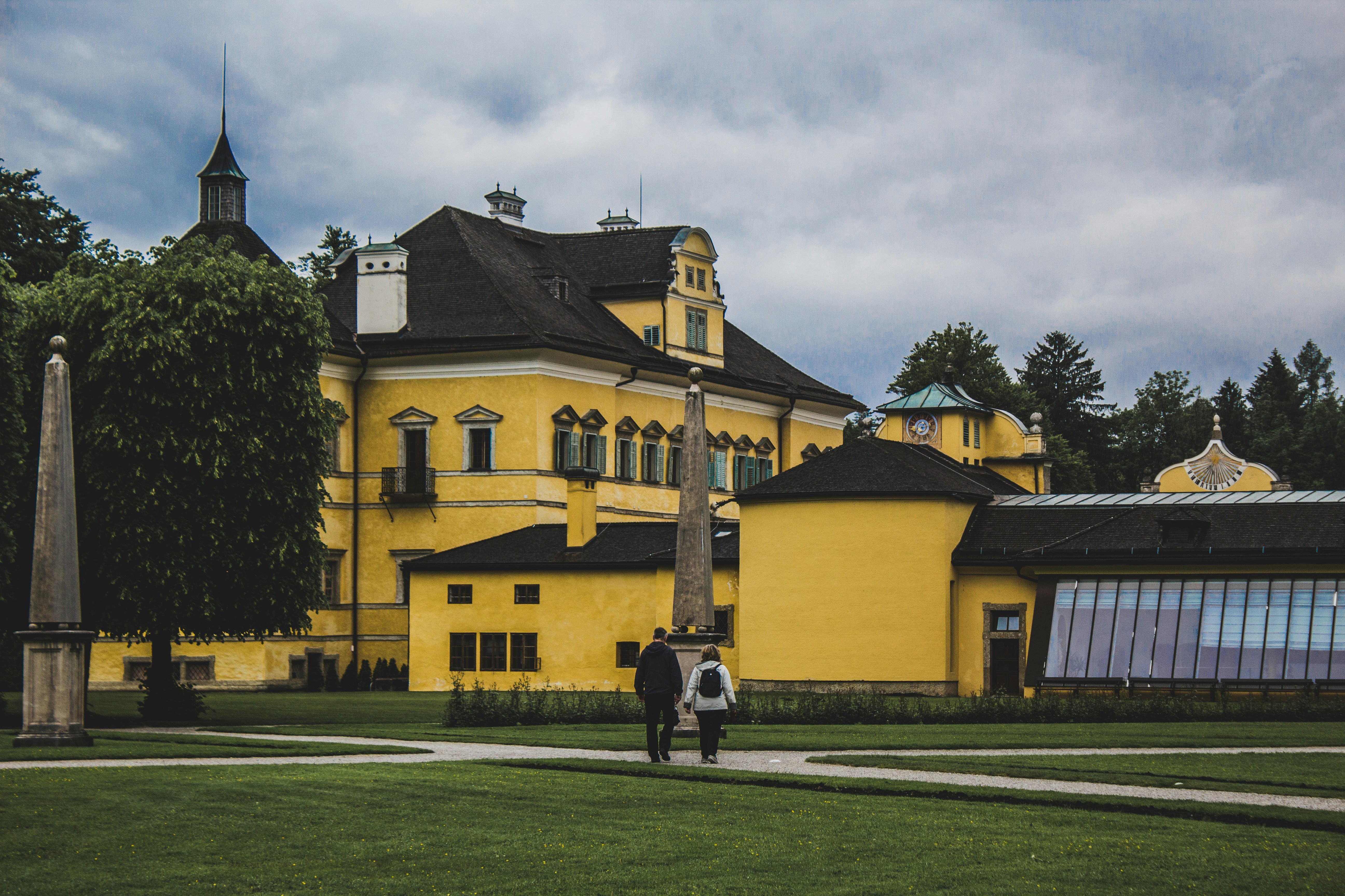 two people walking in front of a yellow building