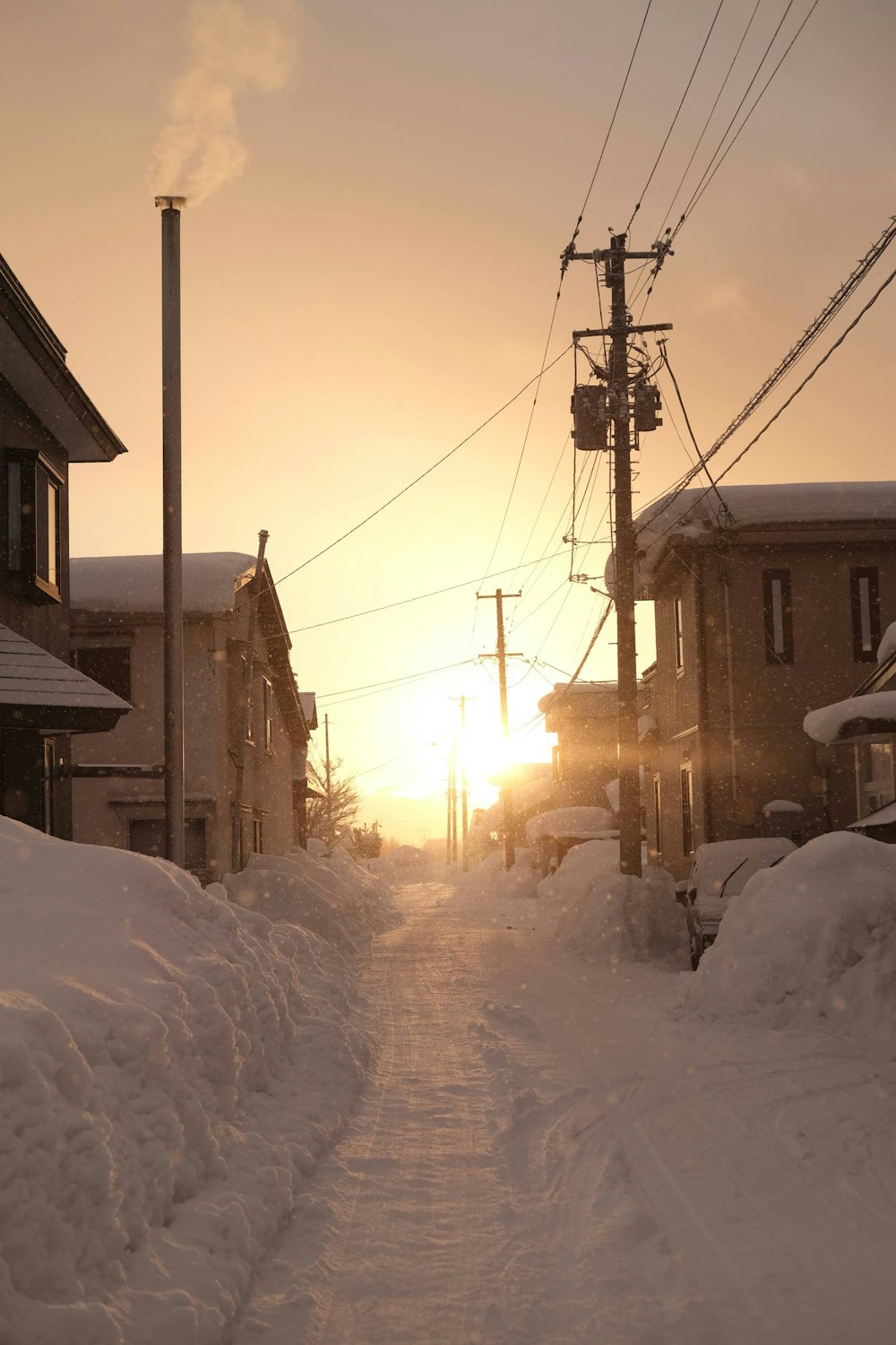 the sun is setting over a snowy street
