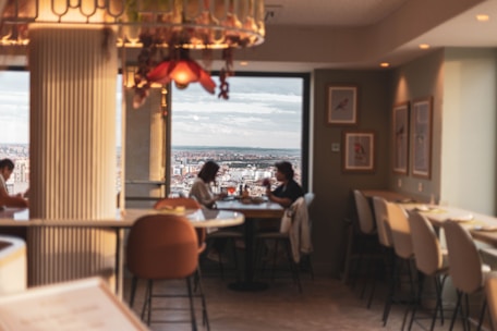 Cozy indoor café scene with people chatting and rain visible through the window.