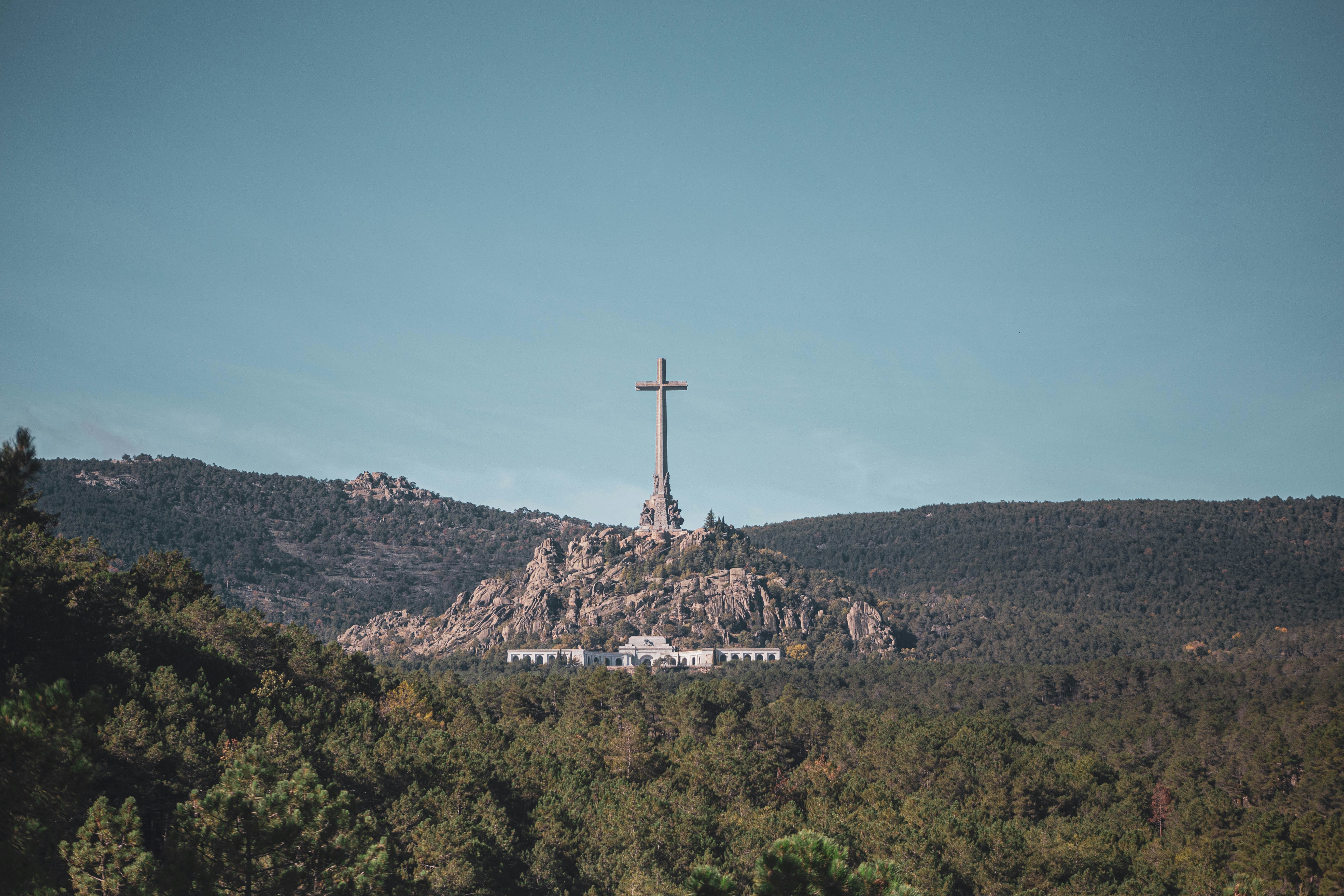 a cross on top of a hill surrounded by trees
