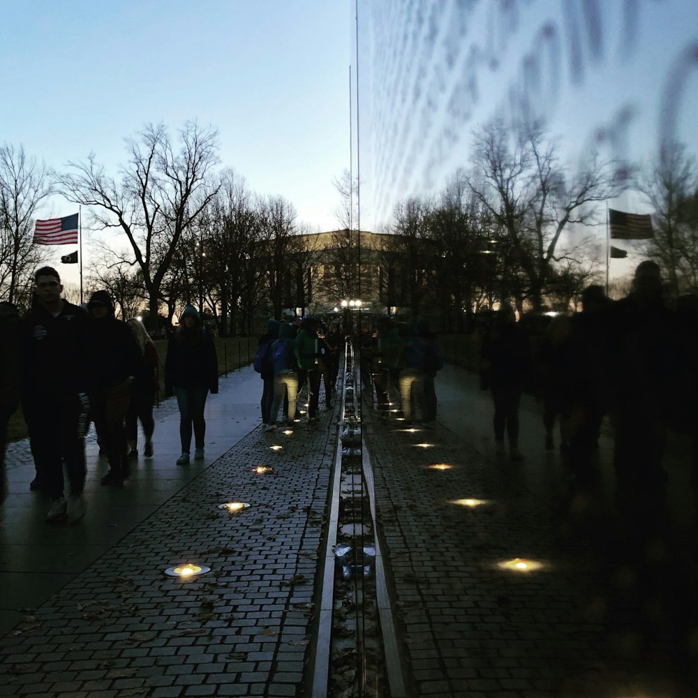 a group of people walking down a sidewalk next to a flag