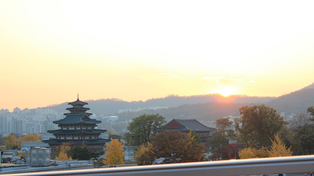 the sun is setting over a city with mountains in the background