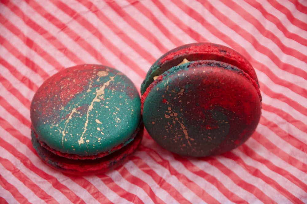 two red and green macaroons sitting on a red and white checkered cloth