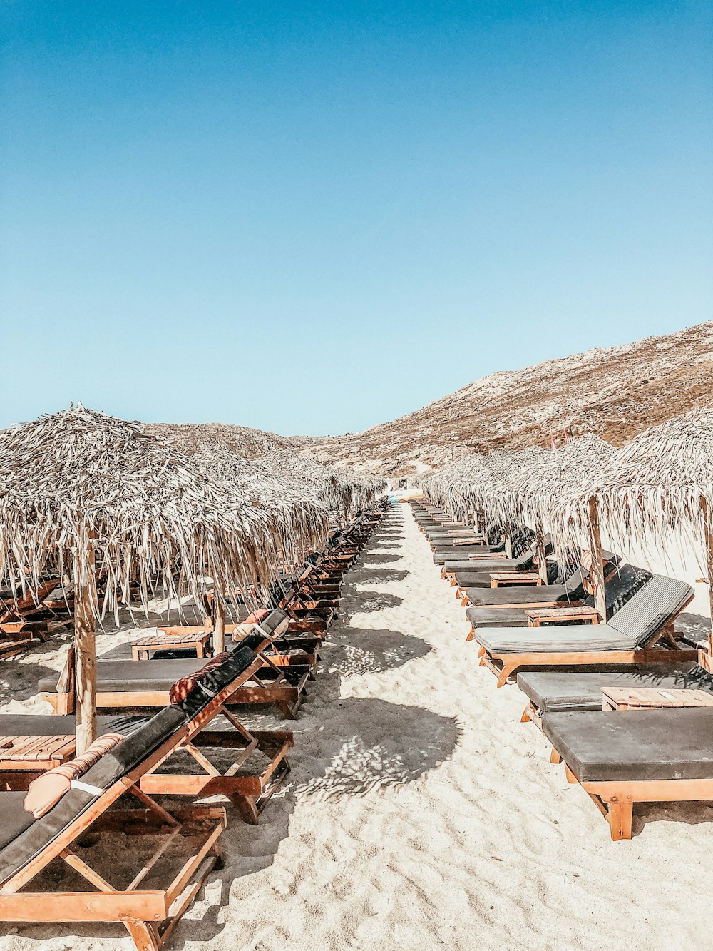 a row of lounge chairs sitting on top of a sandy beach