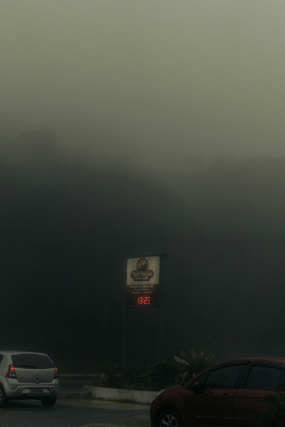 a foggy parking lot with cars parked on the side of the road