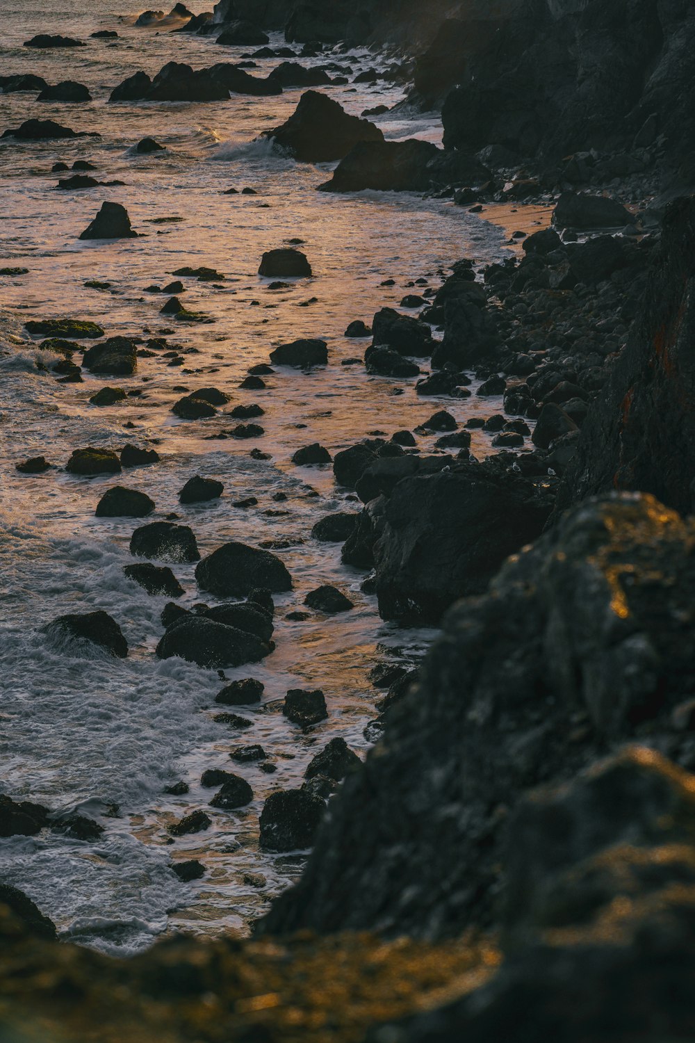 the sun is setting over the ocean and rocks