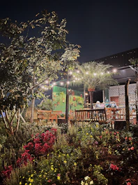 An inviting outdoor loveseat with plush cushions set in a garden under string lights.
