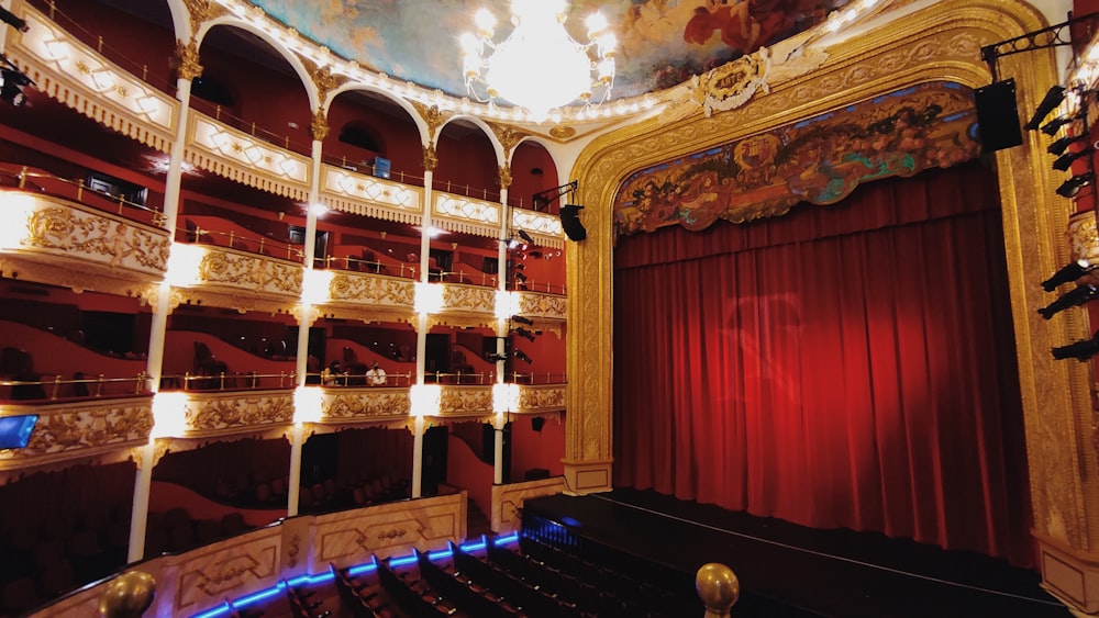 a theater with a red curtain and a chandelier