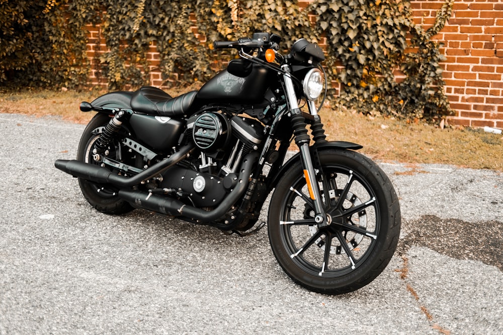 a black motorcycle parked in front of a brick wall