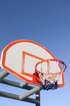 High school athlete practicing basketball on an outdoor court under a clear sky