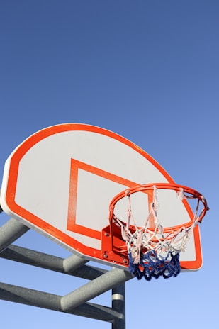 A student holding a basketball on the court, ready to shoot a hoop under a clear blue sky.