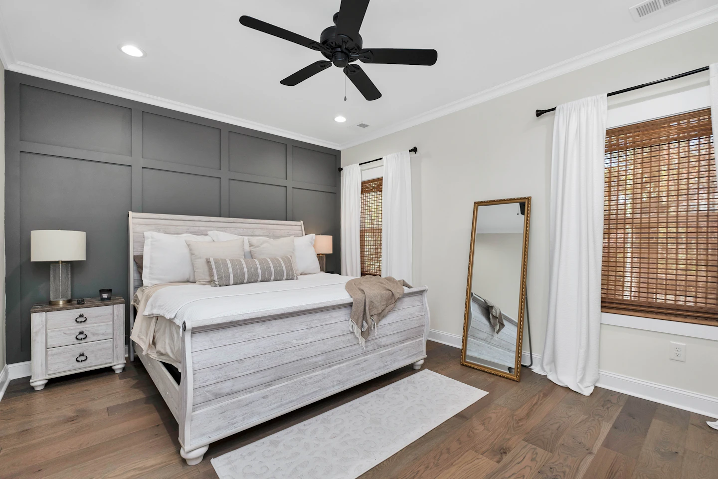 Primary bedroom with a charcoal accent wall and an upholstered bed