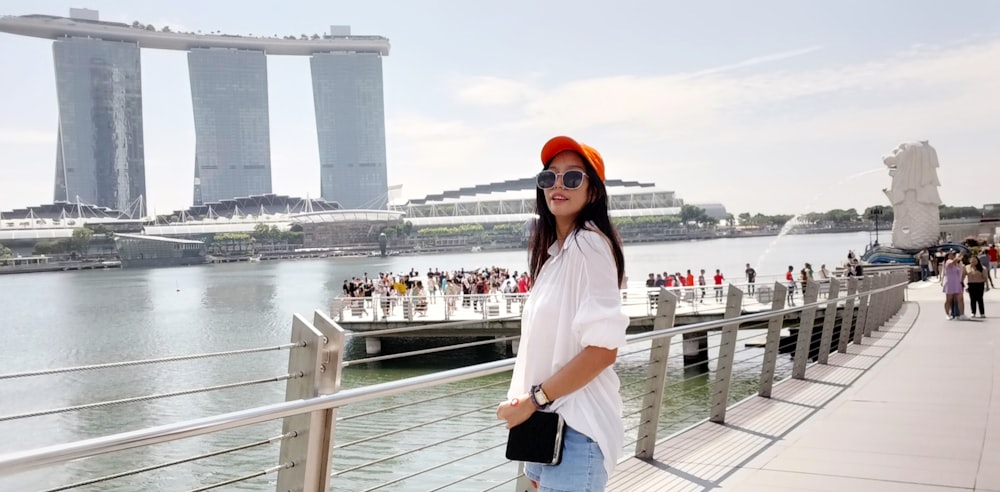 a woman standing on a bridge next to a body of water