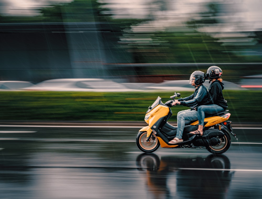 two people riding a motorcycle on a rainy day