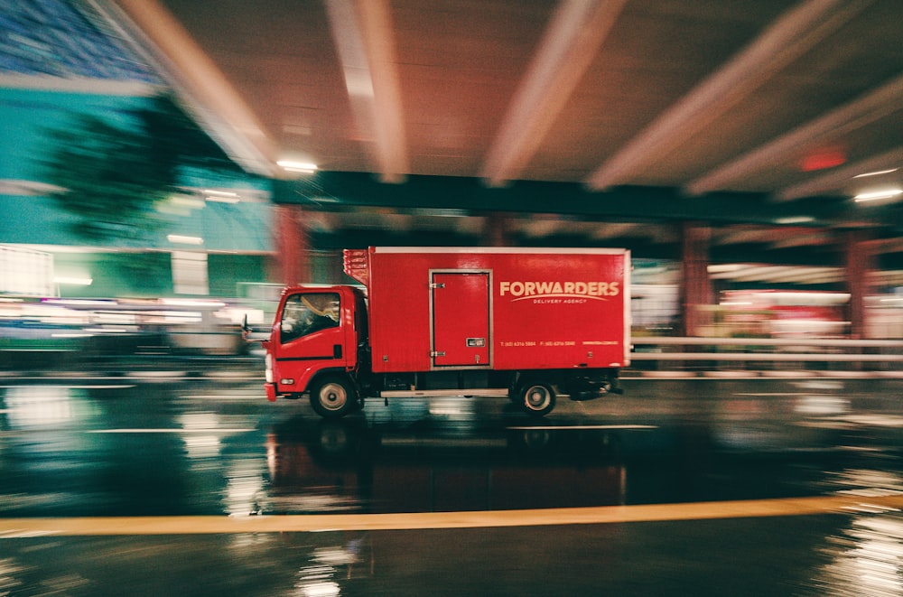 a red truck driving down a wet street