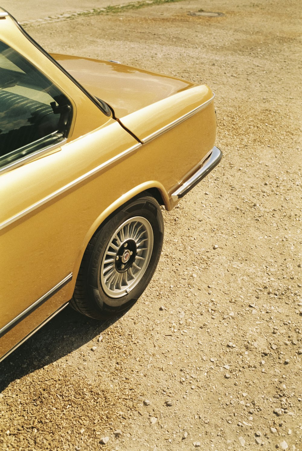 a yellow car parked on a dirt road