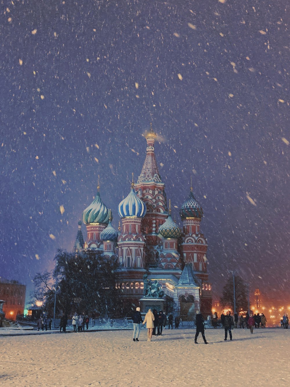 people walking in the snow in front of a building