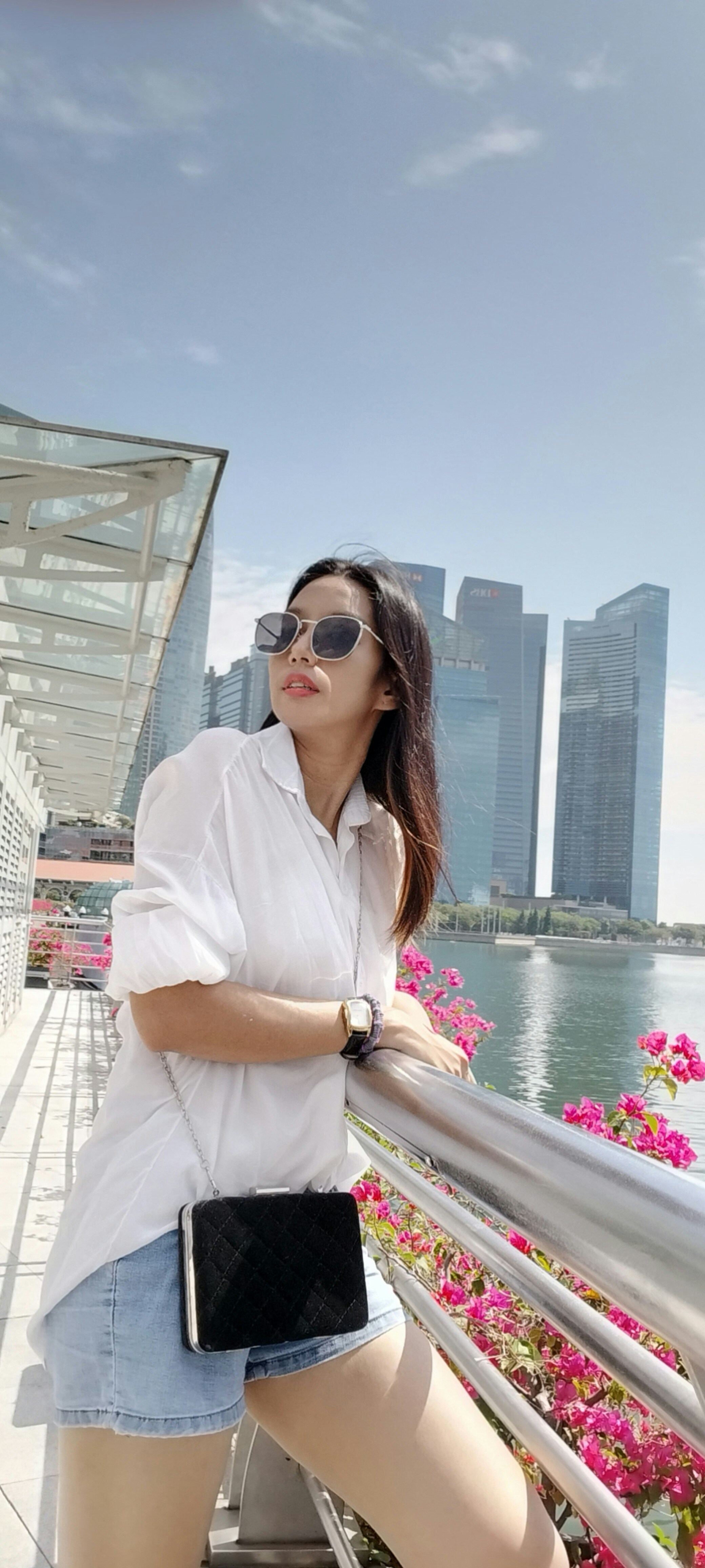 a woman is standing on a bridge with her hand on her hip