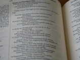 A close-up view of an open book displaying Biblical text. The pages feature chapters and verses with headings such as 'Woes and judgments' and text in a traditional font. The content includes structured, numbered lines.