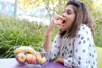 Smiling customer enjoying banana chips outdoors with green foliage in the background.