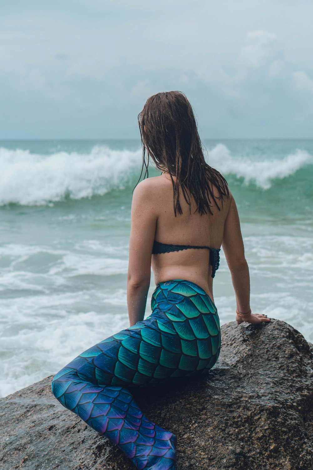 Eine Frau sitzt auf einem Felsen am Meer