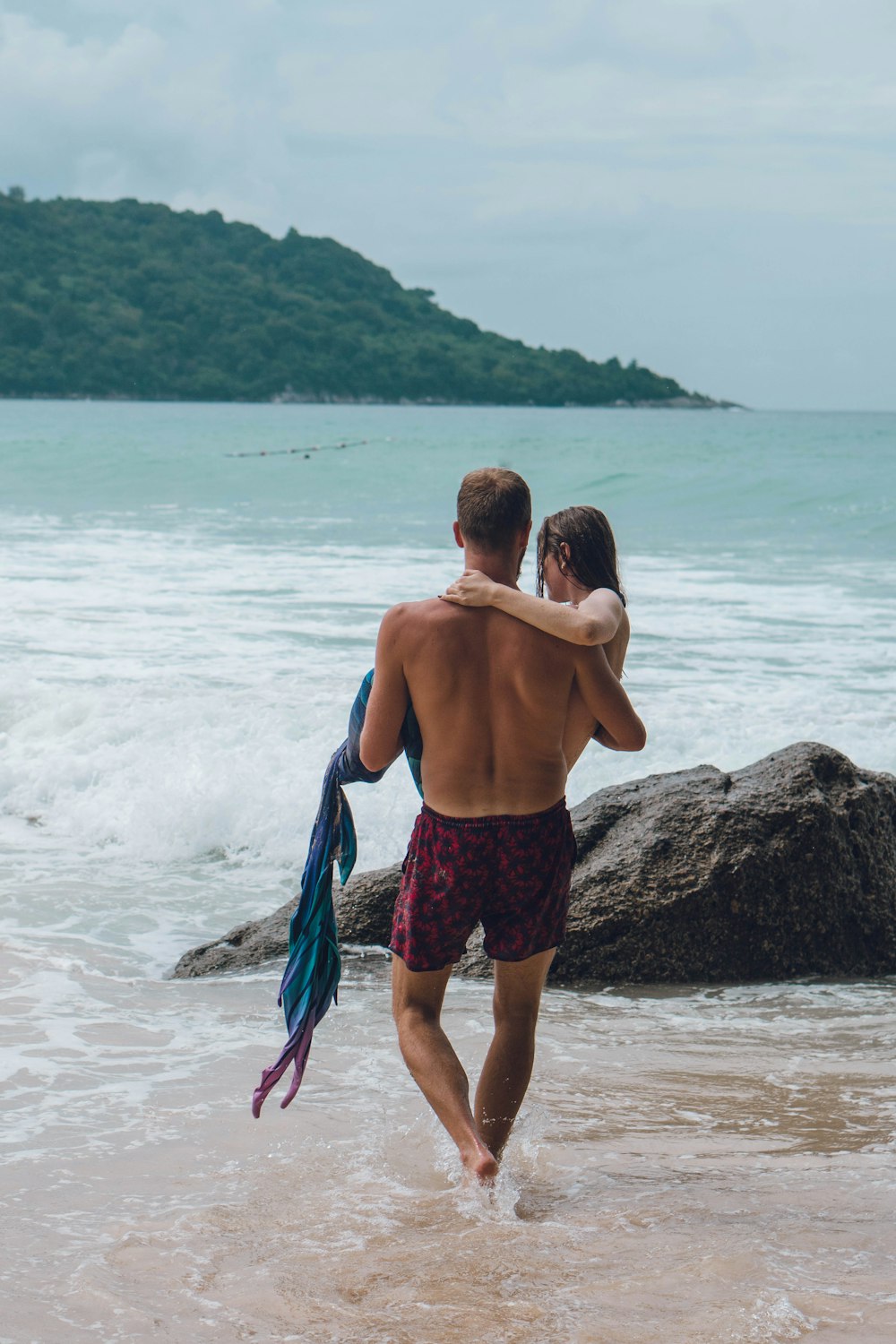 a man and a woman walking into the ocean