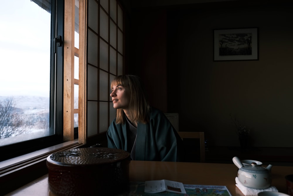 a woman sitting at a table looking out a window