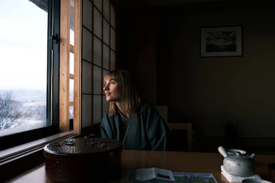 a woman sitting at a table looking out a window