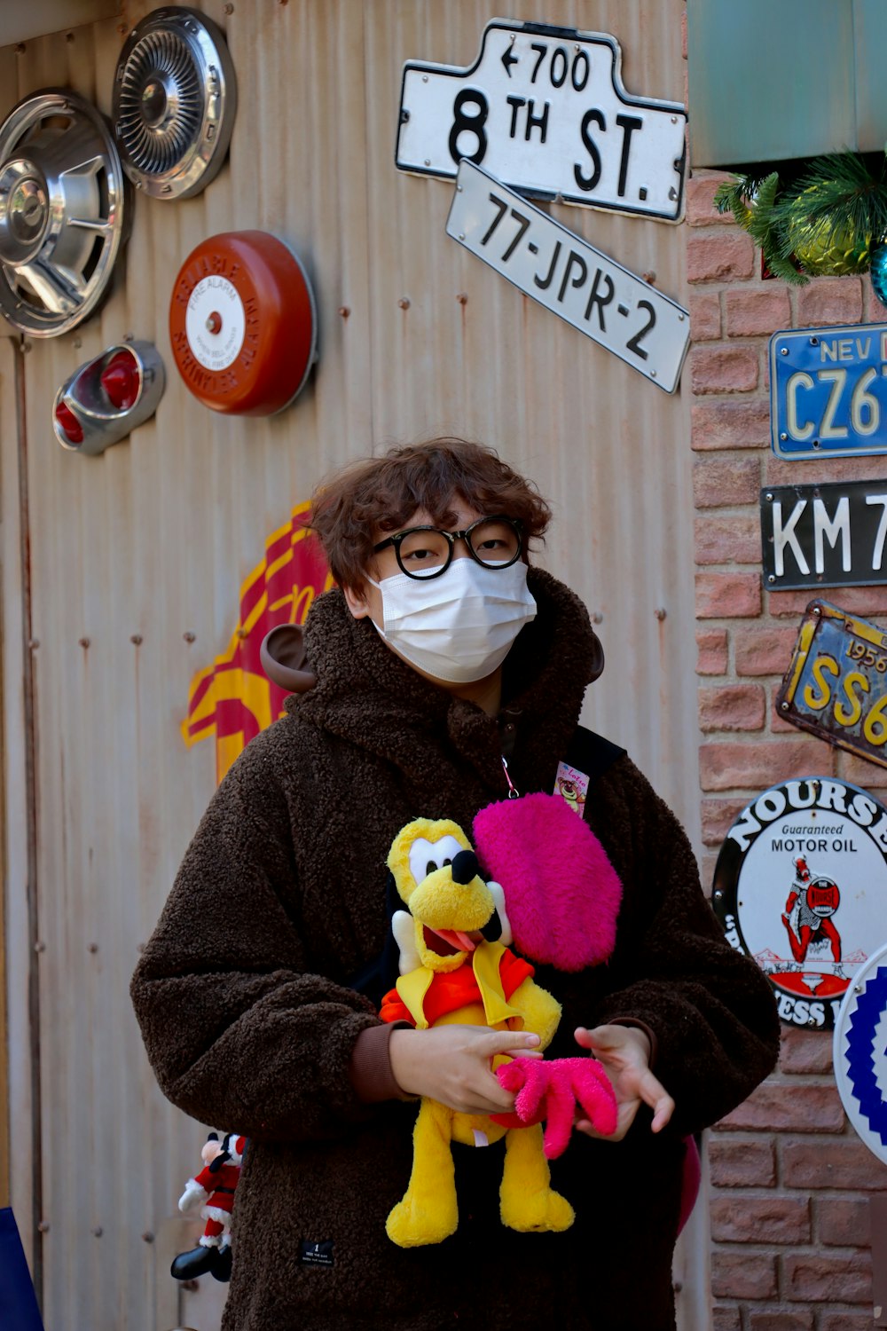 a person wearing a face mask holding a stuffed animal