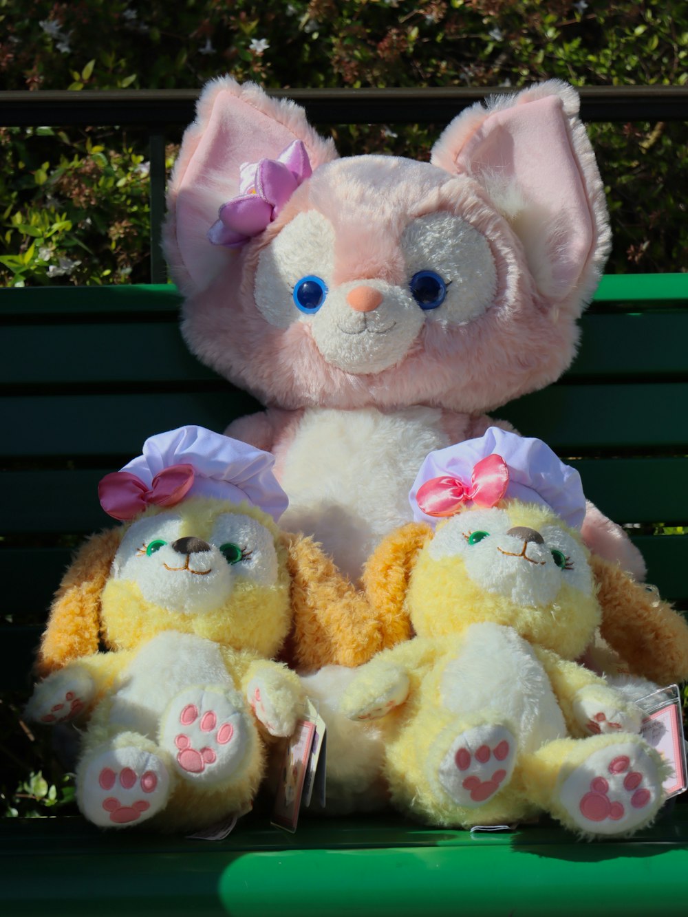 two stuffed animals sitting on a green bench