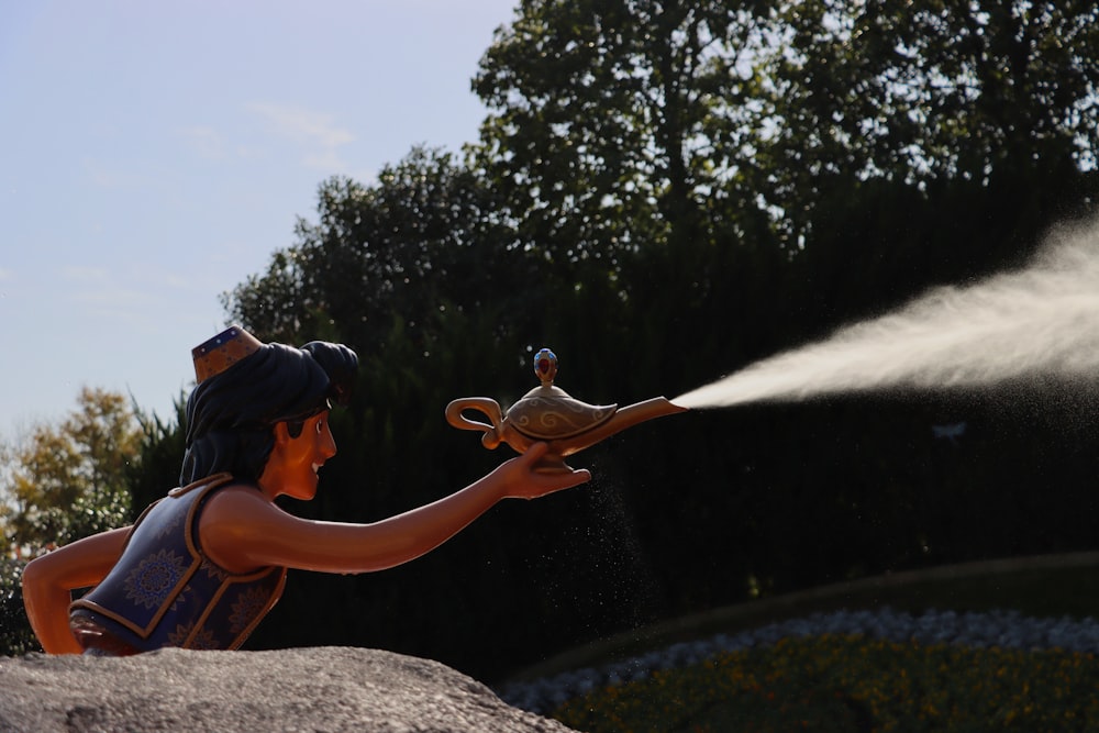 a statue of a person spraying water on a bird