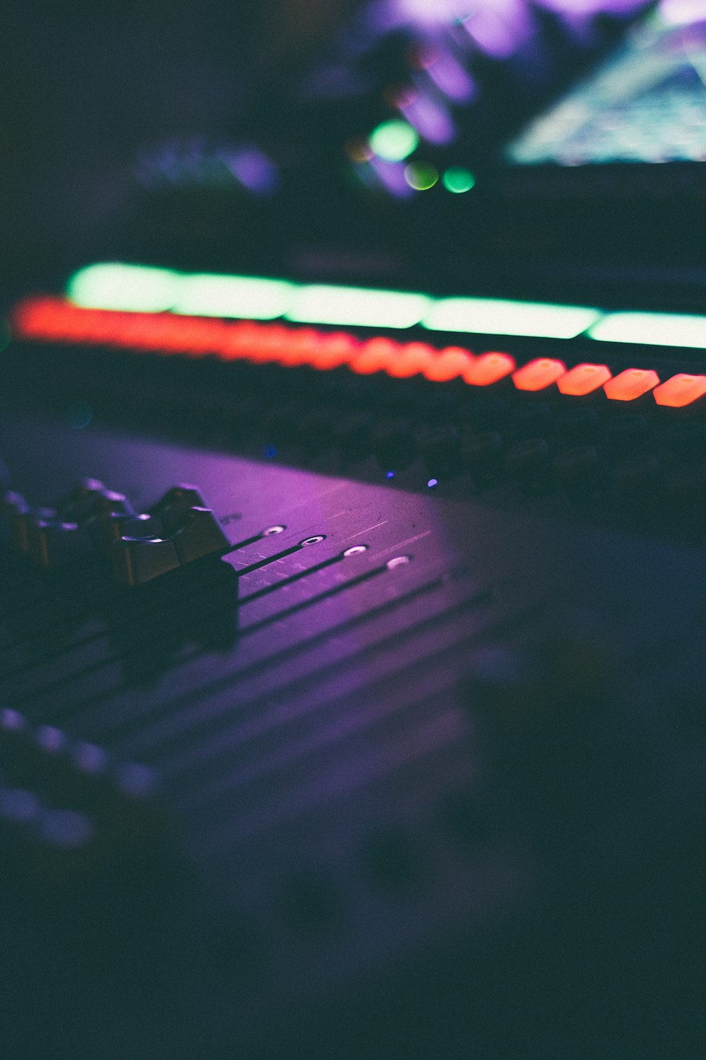 a close up of a sound board with lights in the background