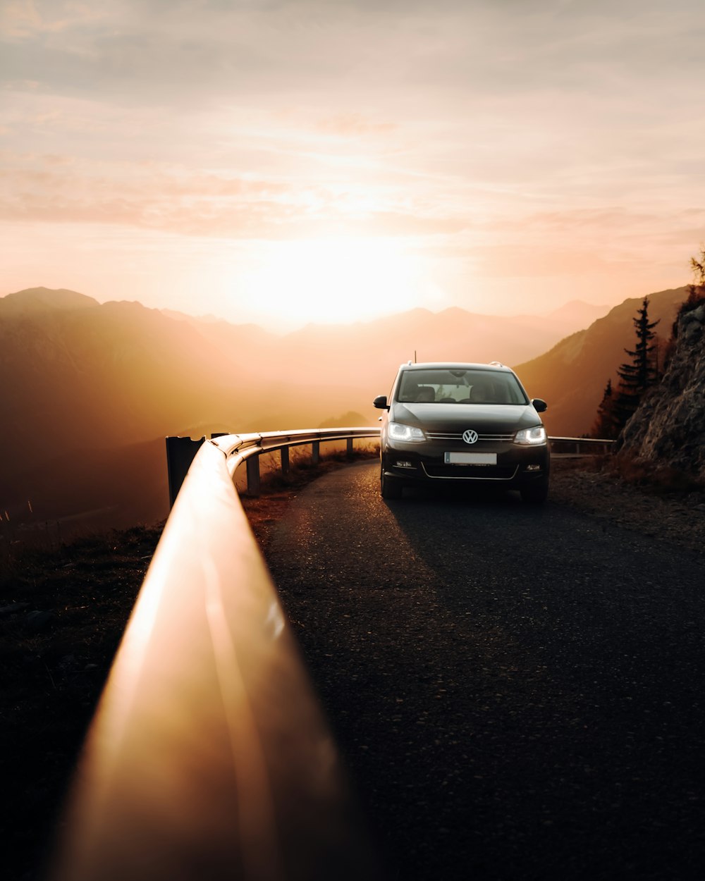 a car driving down a road with the sun behind it