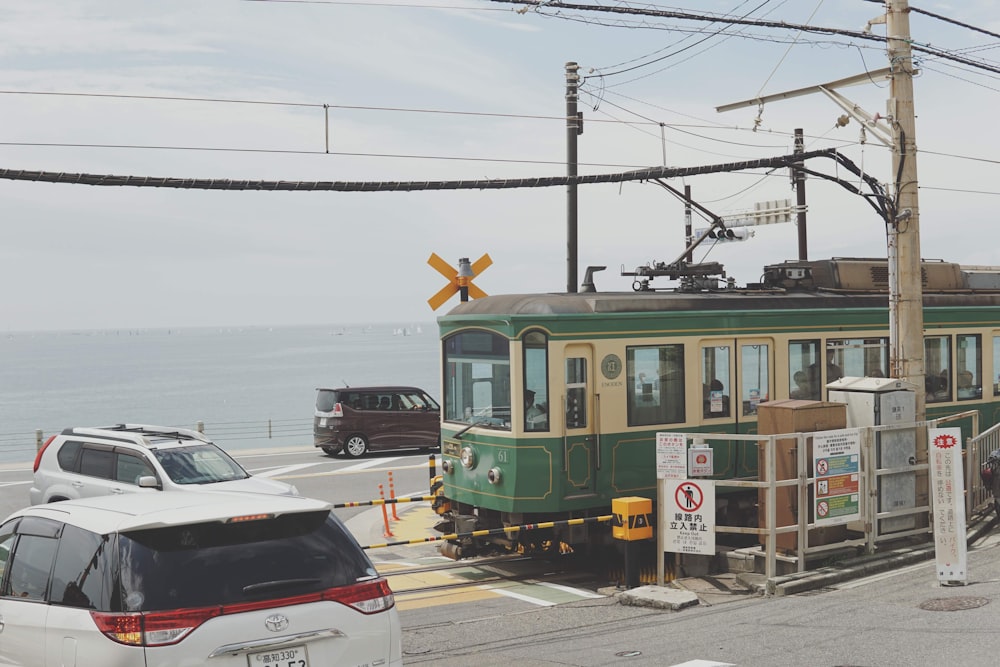 Ein grüner und gelber Zug, der die Gleise entlang des Ozeans fährt