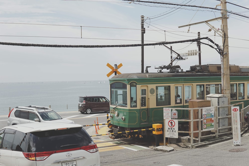 a green and yellow train traveling down tracks next to the ocean