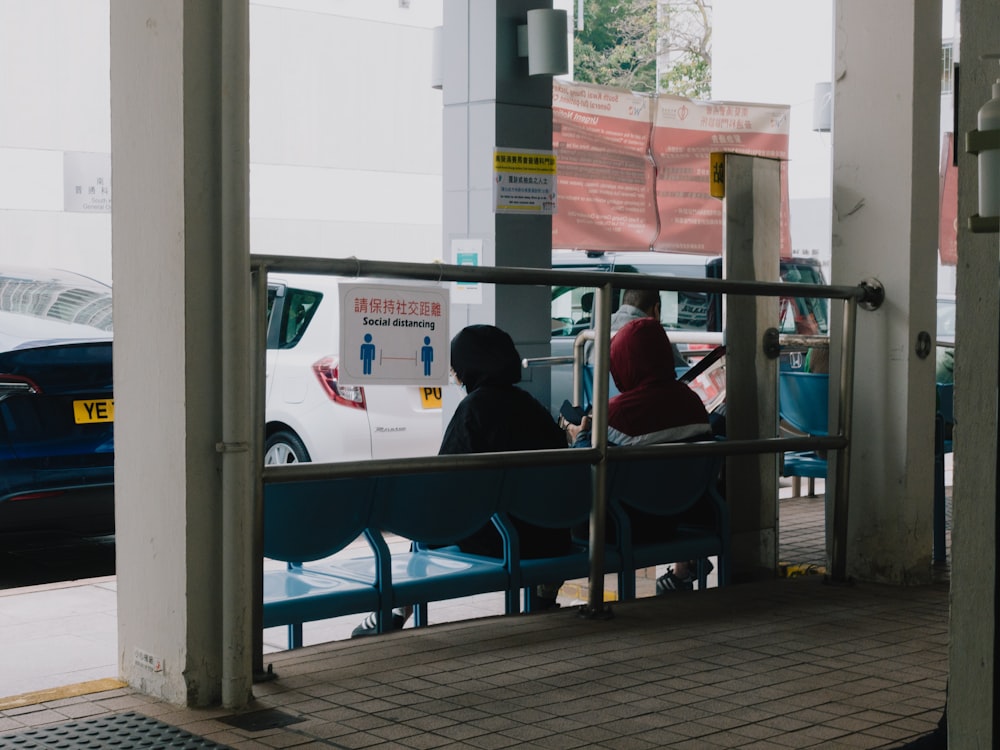 a couple of people sitting on top of a blue bench