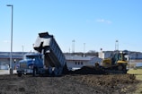 a dump truck is dumping dirt in front of a building