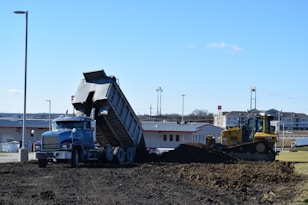 a dump truck is dumping dirt in front of a building