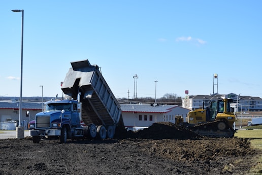 a dump truck is dumping dirt in front of a building