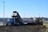 A dump truck unloading soil at a railway construction site surrounded by green hills.